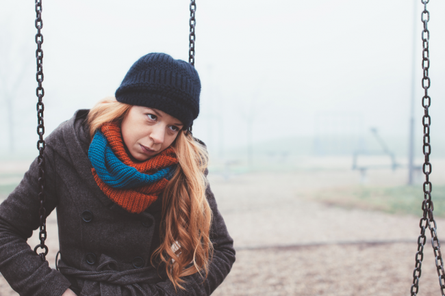 Person in winter clothes playing alone on a swing. 