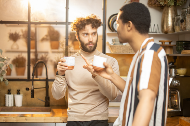 A couple talking about something important in the kitchen while sharing a cup of tea.