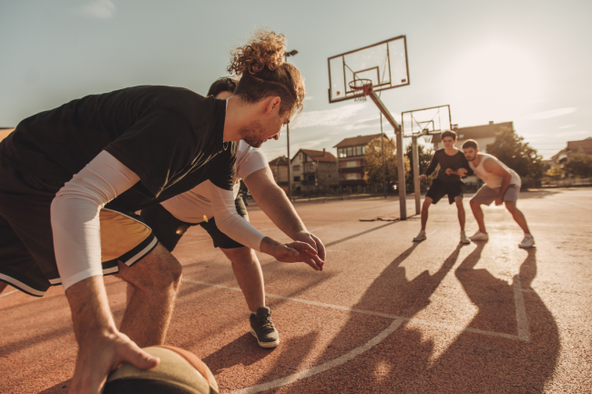 A group of four guy friends playing basketball. 