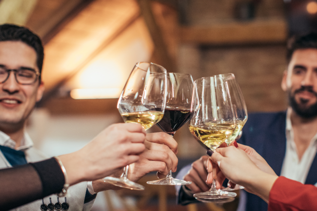 Two male friends in office outfits and two other people make a toast with wine. 