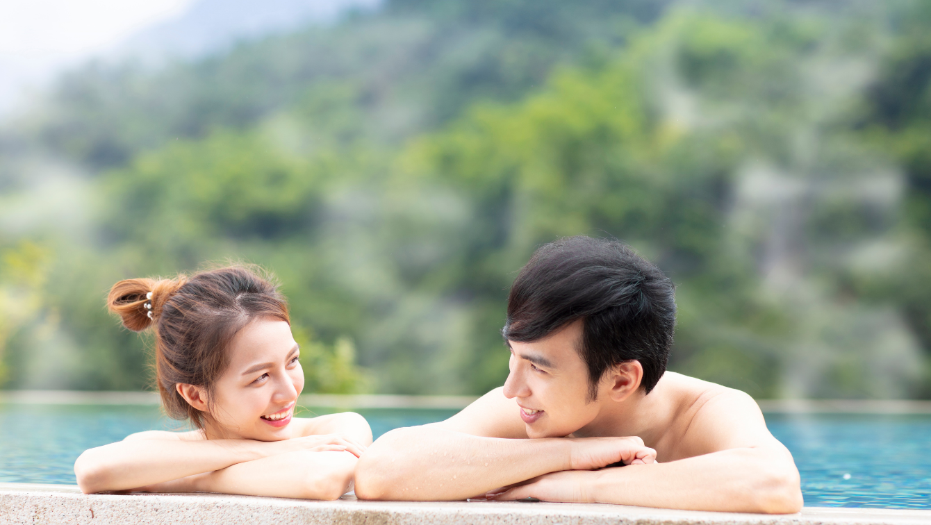 A couple in a hot spring looking at each other and smiling. 