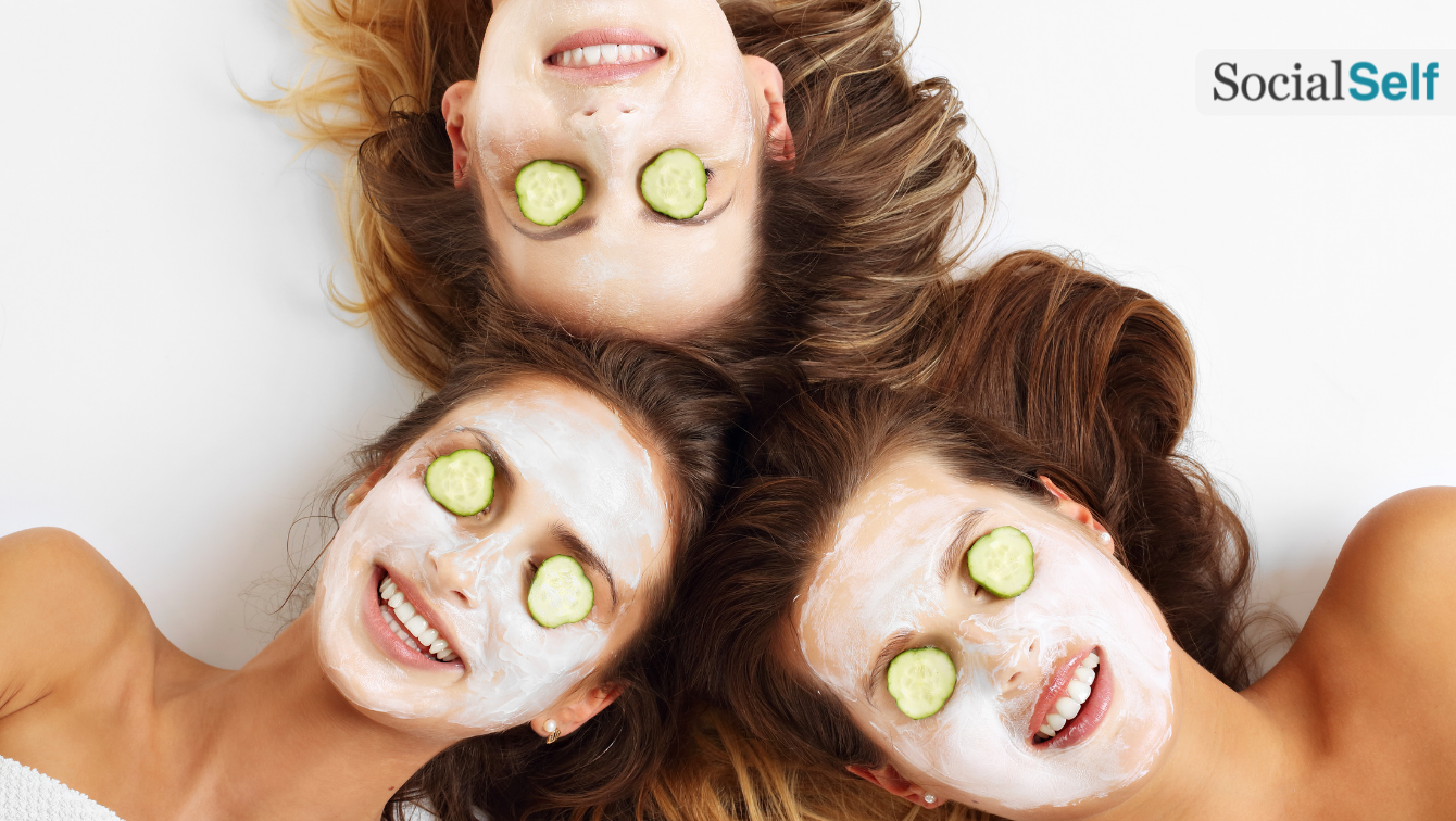 Three friends with cucumbers over their eyes. Their heads seen from above are touching in a circle. 