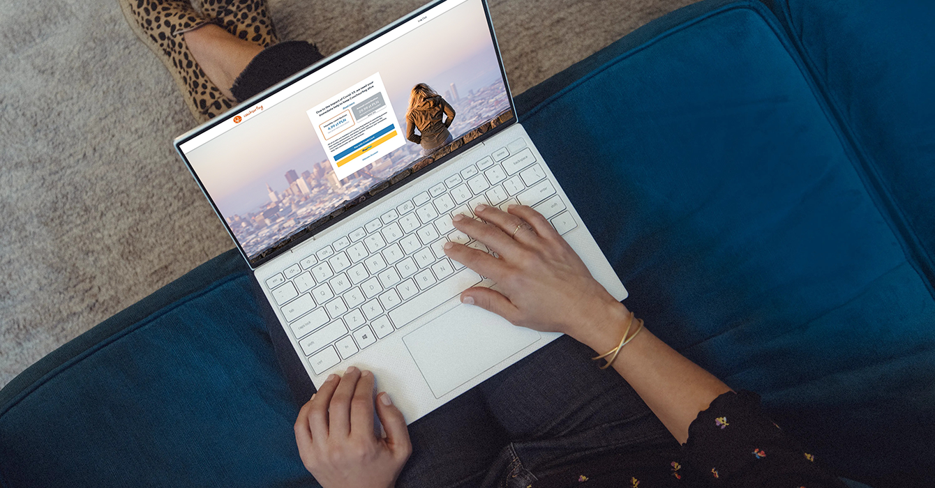 A person sitting on the sofa with a notebook on their lap navigating on CouchSurfing